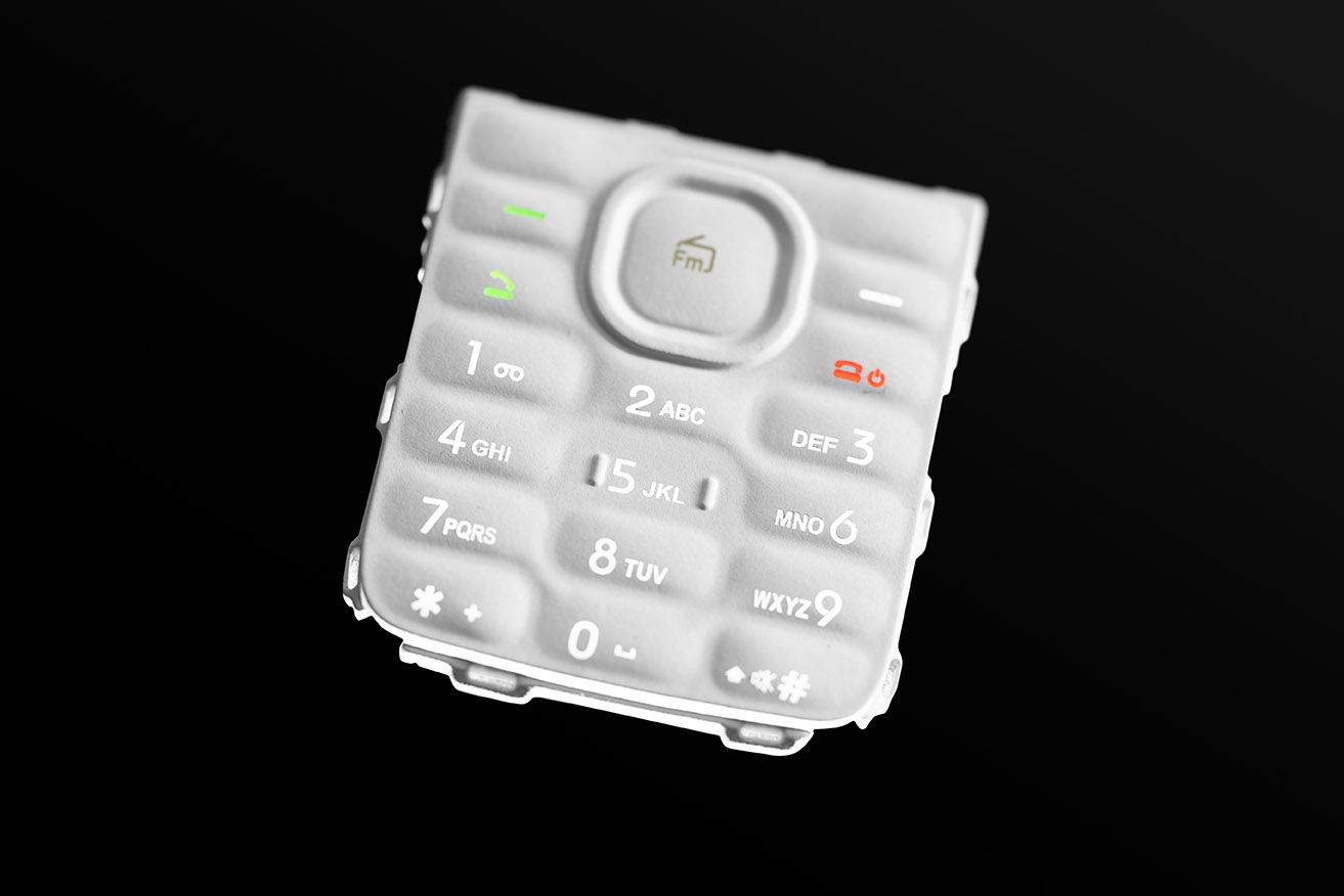 A white keypad for a cell phone whose lettering was produced by laser ablation. 